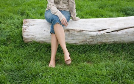 坐在草地枯木上的休闲美女腿部特写图片
