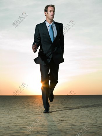 沙漠中奔跑的外国商业男人图片