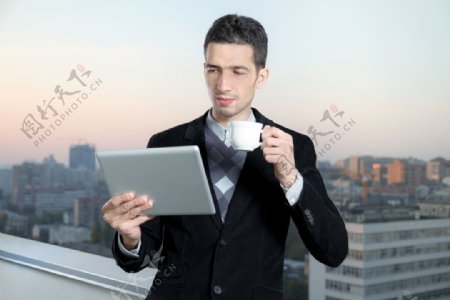喝茶拿着触屏电脑的商务男士图片