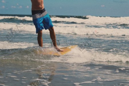 男人穿着蓝色和白色沙滩裤虽然冲浪