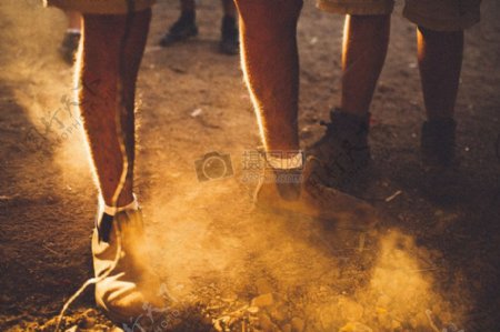 人穿着棕色靴子和白袜子站在泥地面尘土飞扬