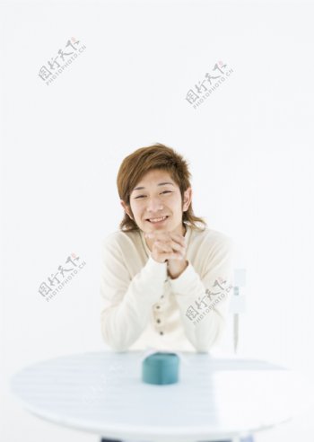 坐在桌子旁边的微笑男生图片