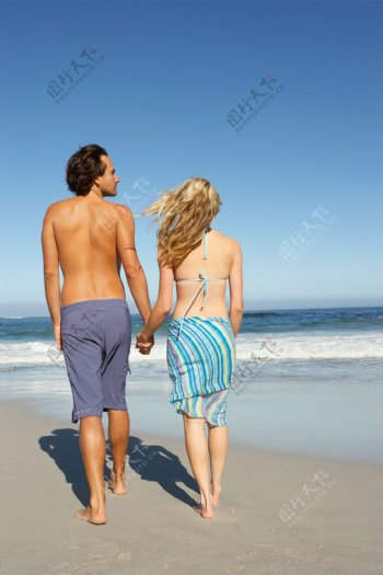 在海边牵手散步的夫妇图片