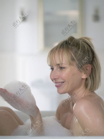 浴缸里手捧白色泡沫的女人图片