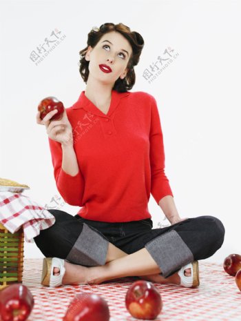 手拿苹果坐着的漂亮性感美女图片