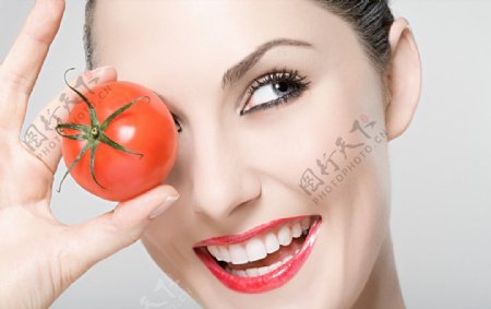 拿西红柿挡住一只眼睛的美女图片