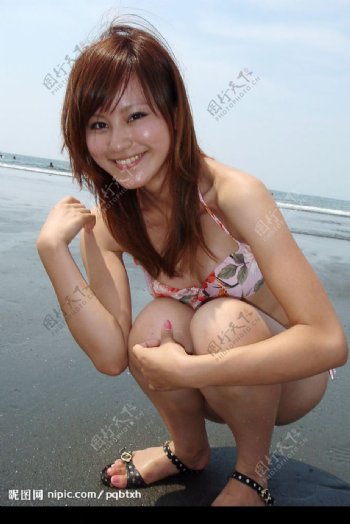 漂亮又淘气的混血美眉蹲在沙滩上图片