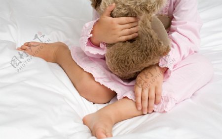 床上抱着玩具熊的孩子图片