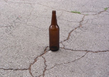 水泥地上的棕色酒瓶图片