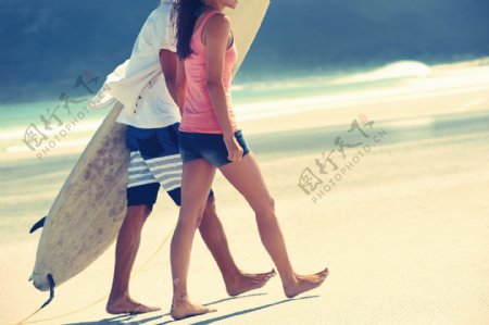 沙滩上拿着冲浪板的情侣图片