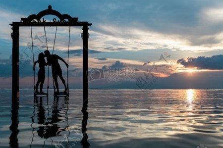 情侣剪影日落期间在平静的海面上亲吻