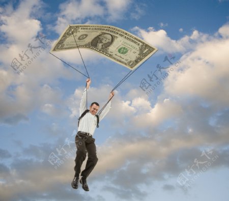 男人乘着大型钞票图案降落伞高清大图图片