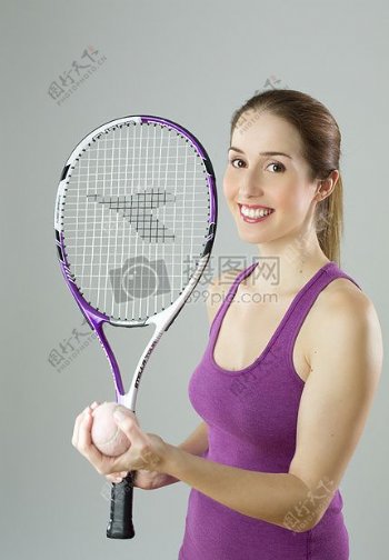 女人穿着紫色背心控股紫色和白色球拍和草地网球球