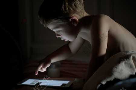 在夜晚里玩电脑的小男孩图片