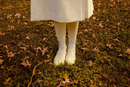 女人在白色礼服和白袜子搭配和鞋子站在绿草