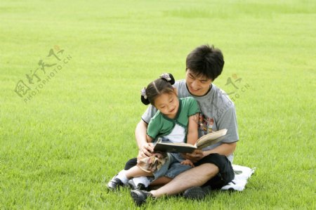 草地上看书的父女图片