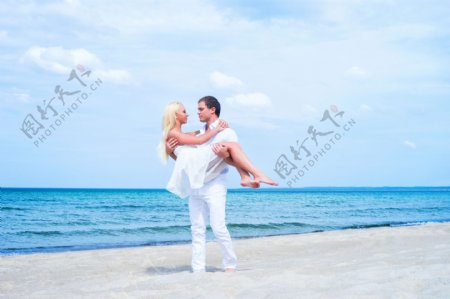 沙滩上抱着妻子的男士图片