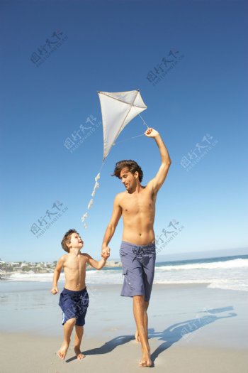 沙滩上放风筝的父子图片