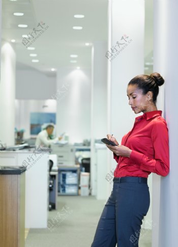 靠在墙壁玩手机的女人图片